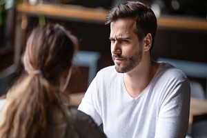 couple sitting at a table having a conversation with man with a questioned expression