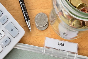 calculator and jar with coins in it labeled with an IRA tag