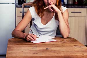 Woman writing down a list of her assets, records and debts