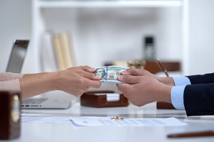 a couple pulling a hundred dollar bill with their wedding rings on the table