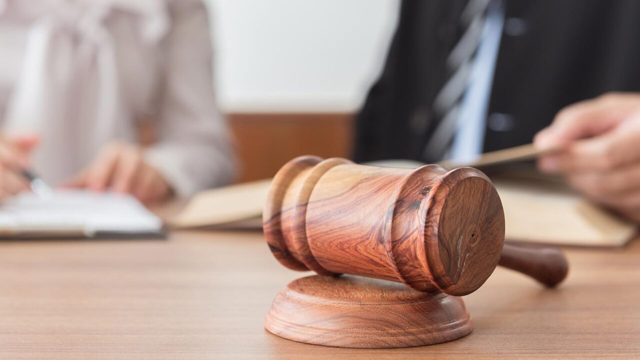 a judge gavel with family attorney's in the background