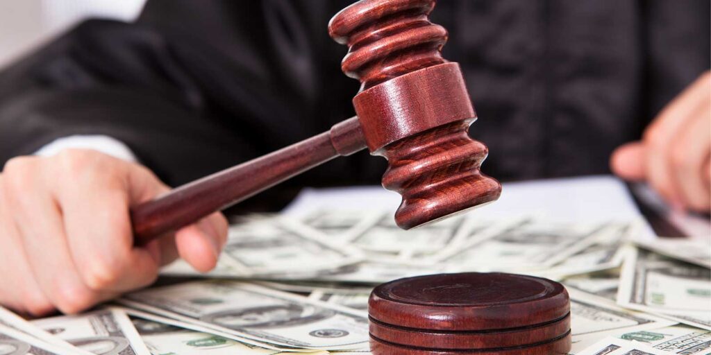 a jugde with holding a gavel with dollar bills on his desk