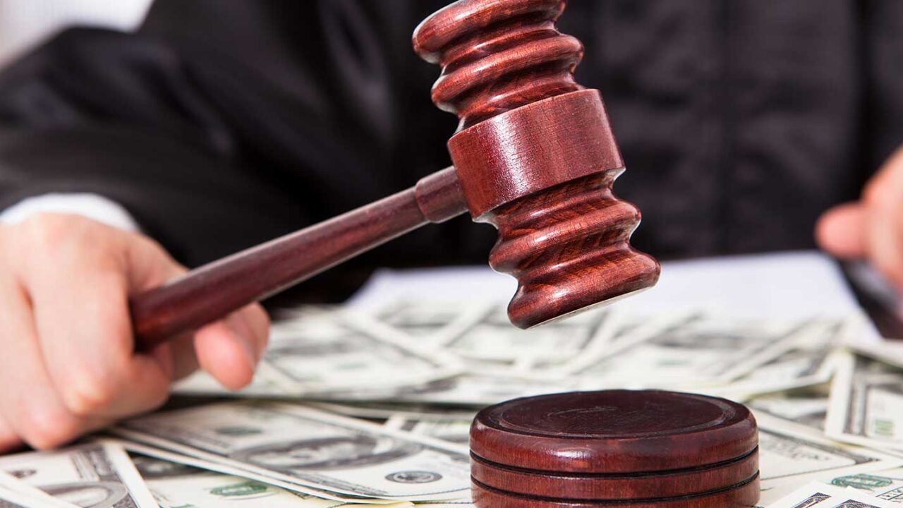 a jugde with holding a gavel with dollar bills on his desk