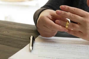 man signing divorce agreement and taking ring out