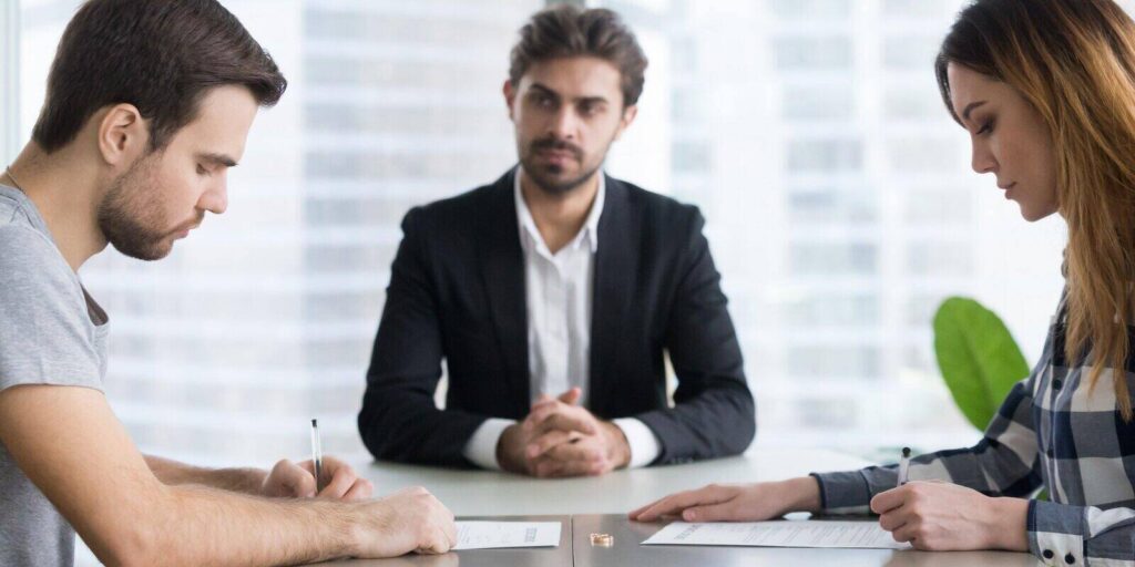 couple signing decree papers getting divorced in lawyers office