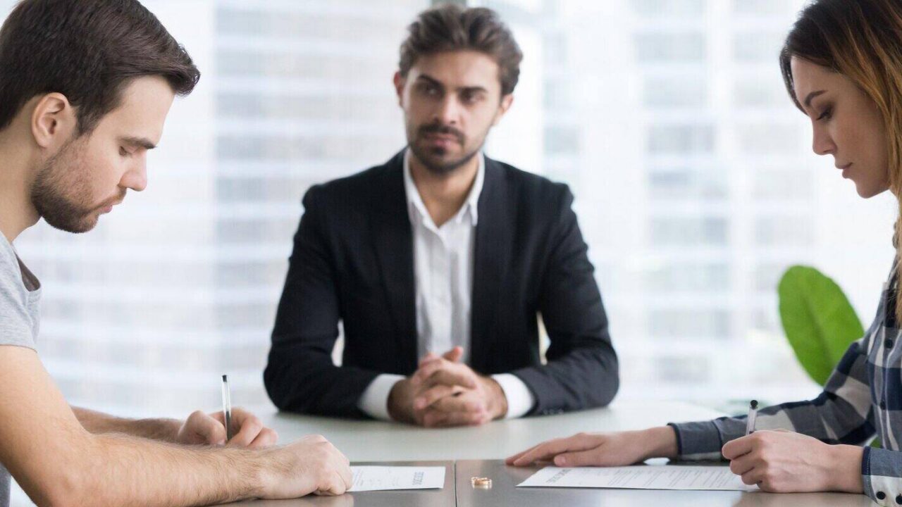 couple signing decree papers getting divorced in lawyers office