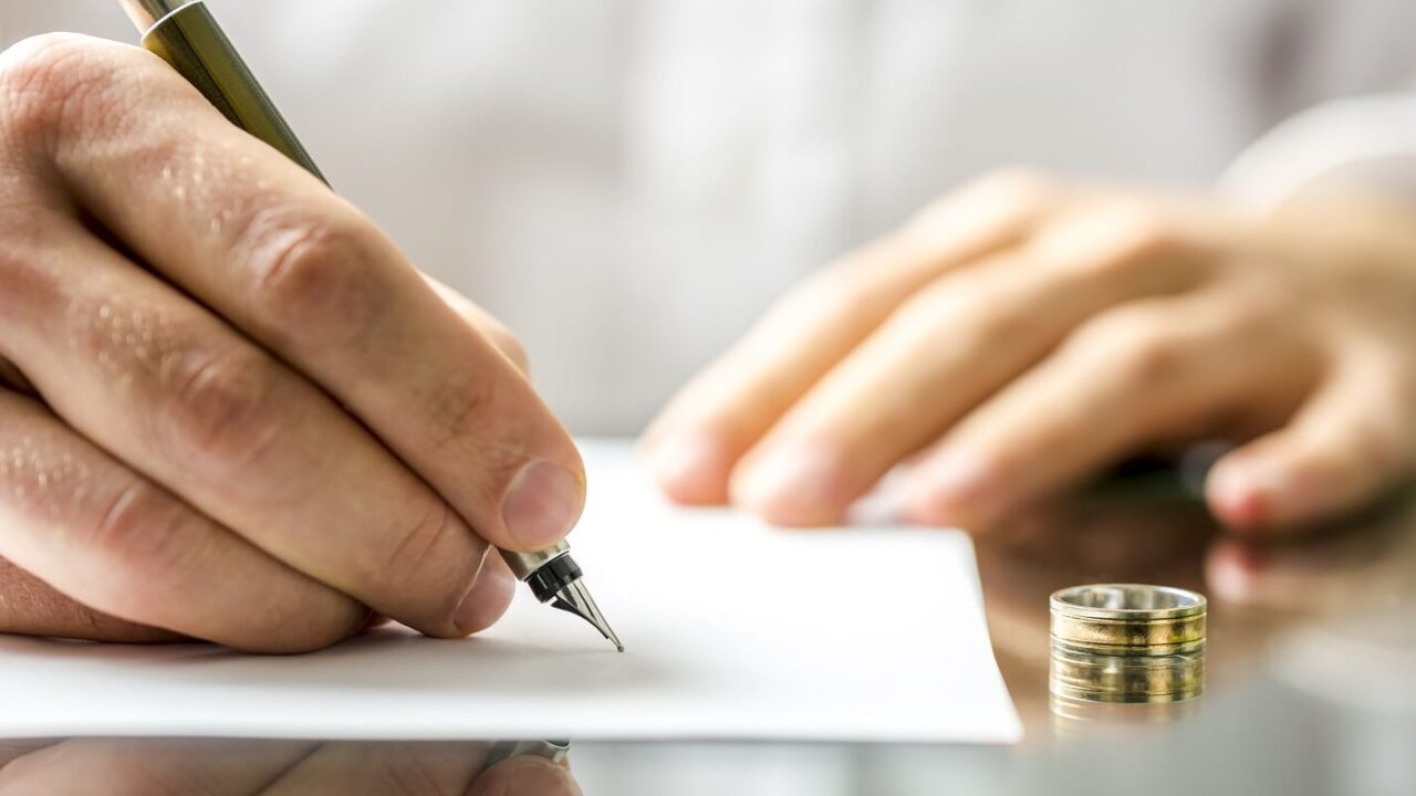 closeup of a man signing divorce papers