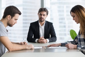 spouses couple signing decree papers getting divorced in lawyers office