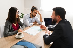 lawyer giving the divorce papers to an unhappy hispanic couple at his office