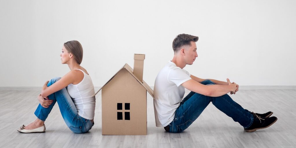 couple sitting against house