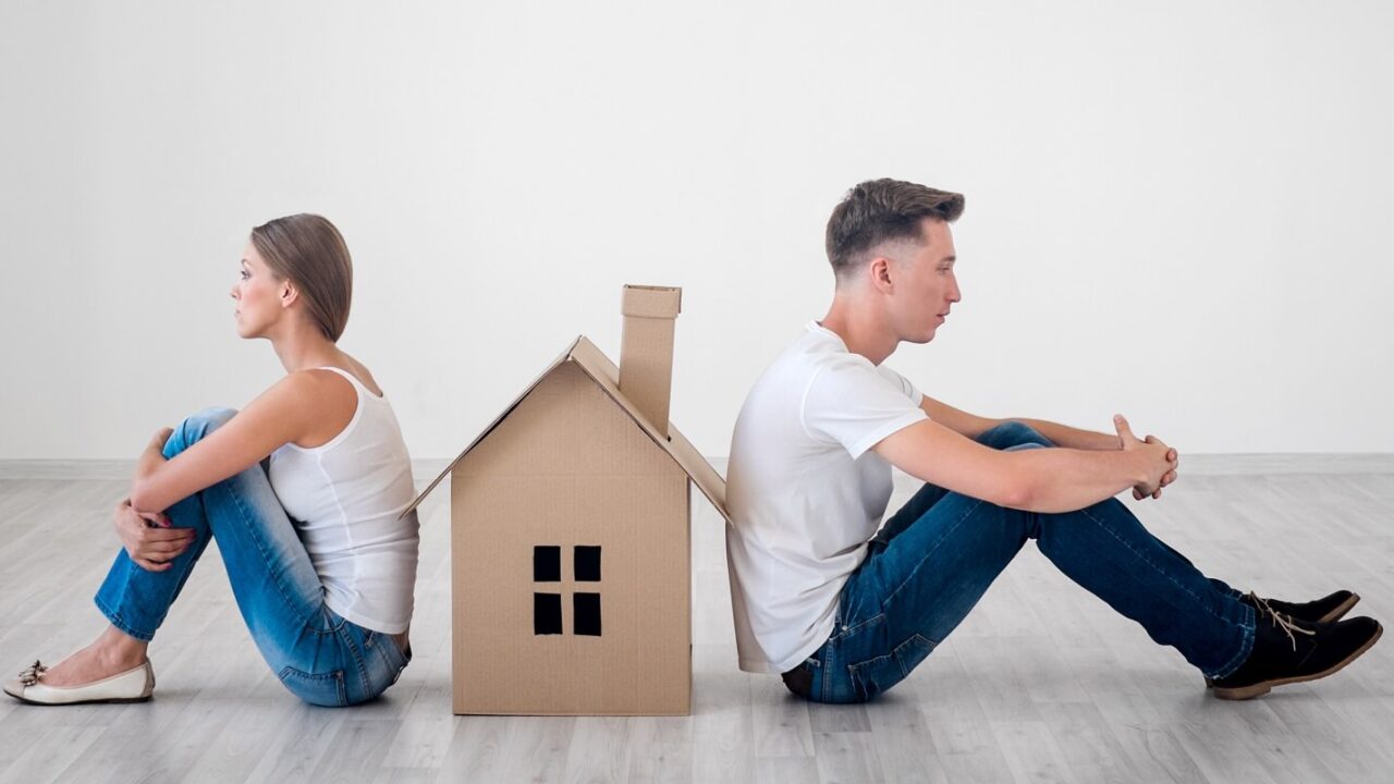 couple sitting against house