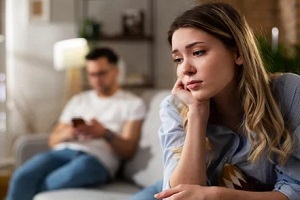 upset women with blurred husband in background