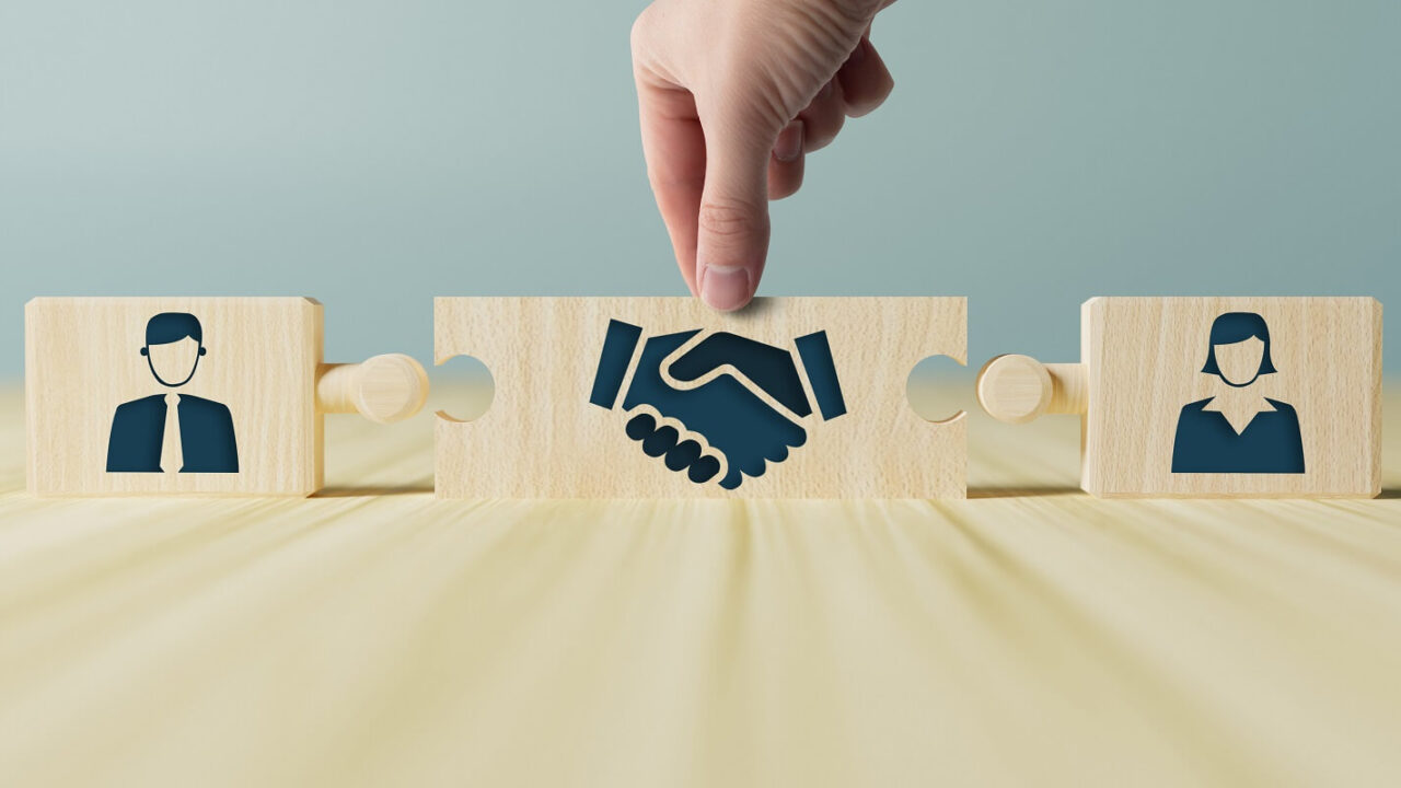 hand holds wooden wooden blocks with icons of a woman and a man and shaking hands in the act of consent