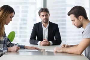 spouses couple signing decree papers getting divorced in lawyers office