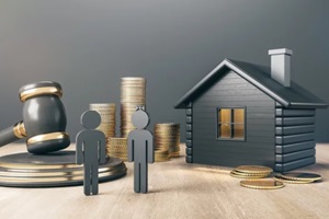 black house with golden coin stacks, male, female and gavel on concrete and wooden background