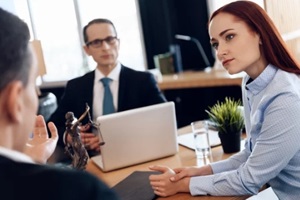 red-haired beautiful woman listens attentively to man looking at divorce attorney