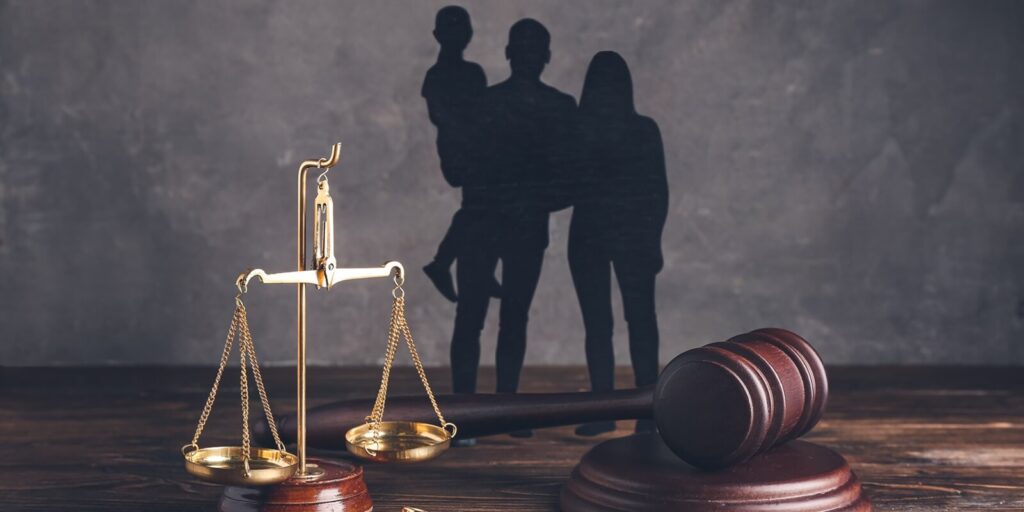 family figures with judge's gavel and justice scales on dark wooden background