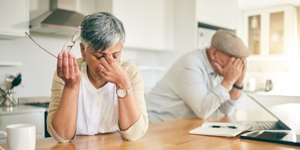 frustrated senior couple, headache and fight in divorce, debt or financial crisis together at home