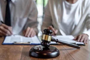 court gavel and a couple signing divorce agreement in a blurred background