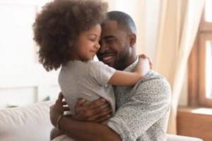 happy african father holding embracing cute little child daughter