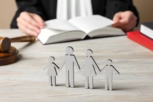 divorce attorney with book sitting at white wooden table, focus on figure of parents and children