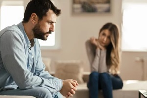 young man feeling sad after arguing with his girlfriend on sofa at home