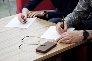 adult woman and a man, sitting at a table in the office, fill out documents or forms