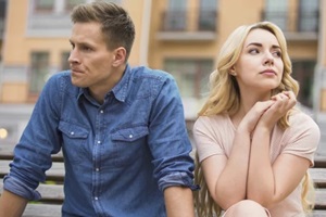 upset man and crying woman sitting on bench, divorce