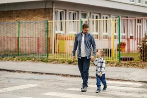 a father and son crossing a crosswalk while holding hands