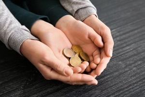 hands of woman and his son holding coins on wooden table