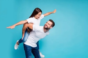 profile side photo of cheerful people holding hands playing piggyback wearing white t-shirt denim jeans isolated over blue background