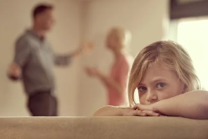 shot of a little girl looking unhappy as her parents argue in the background