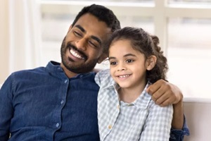 loving young Indian dad and pretty preschool daughter kid looking away with toothy smiles