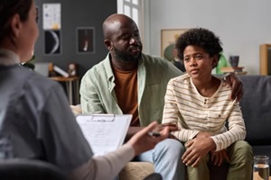 teenage boy listening to psychologist during family therapy session with caring father copy space