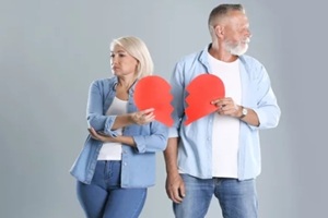 mature couple with torn paper heart on grey background