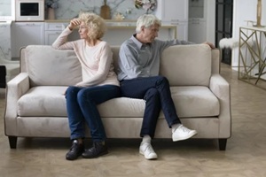 upset old couple sitting on sofa