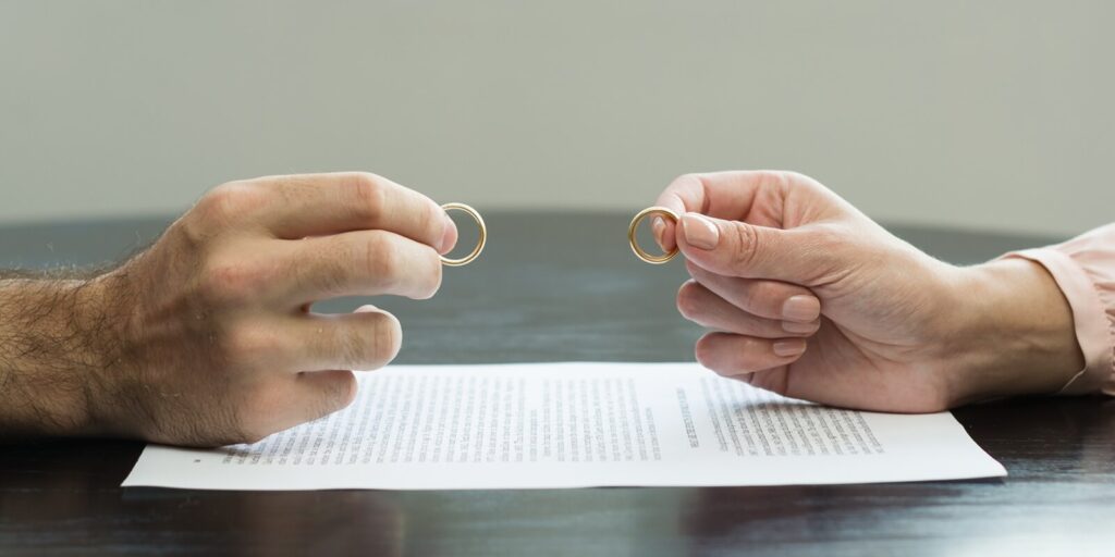 couple holding wedding rings on a divorce agreement