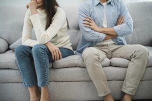 asian women cover her face and sit separately from husband feel disappointed after quarrels at home
