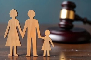 wooden figures of family stand on table in front of gavel