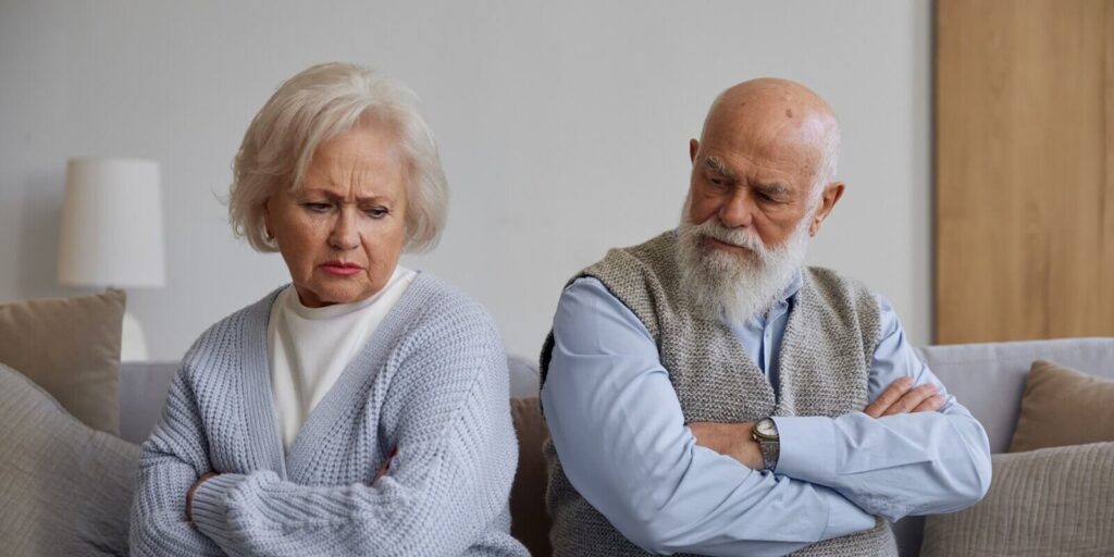unhappy senior couple with frowning face after quarrel silently sitting on sofa