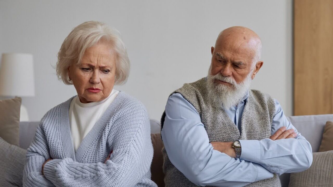 unhappy senior couple with frowning face after quarrel silently sitting on sofa