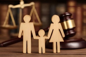 wooden family figures holding hands near gavel and scales of justice