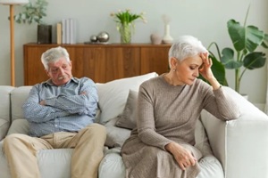 sad mature disappointed woman sitting away from husband after having quarrel