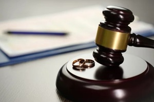 judge gavel with wedding rings and divorce decree