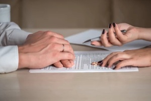 wife and husband signing divorce documents, woman returning wedding ring
