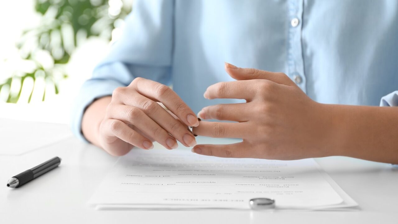 young woman slipping ring off her finger at table, closeup