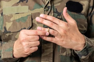 hands of soldier male who is about to taking off his wedding ring