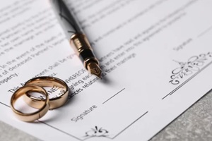 fountain pen and golden wedding rings on grey table, closeup