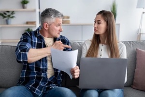 stressed middle-aged man blaming his wife, asking for divorce, holding marriage contract at home