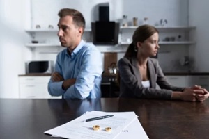 upset couple with marriage rings and divorce papers on the table